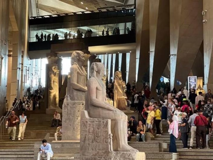 Visitors beside a monumental museum statue