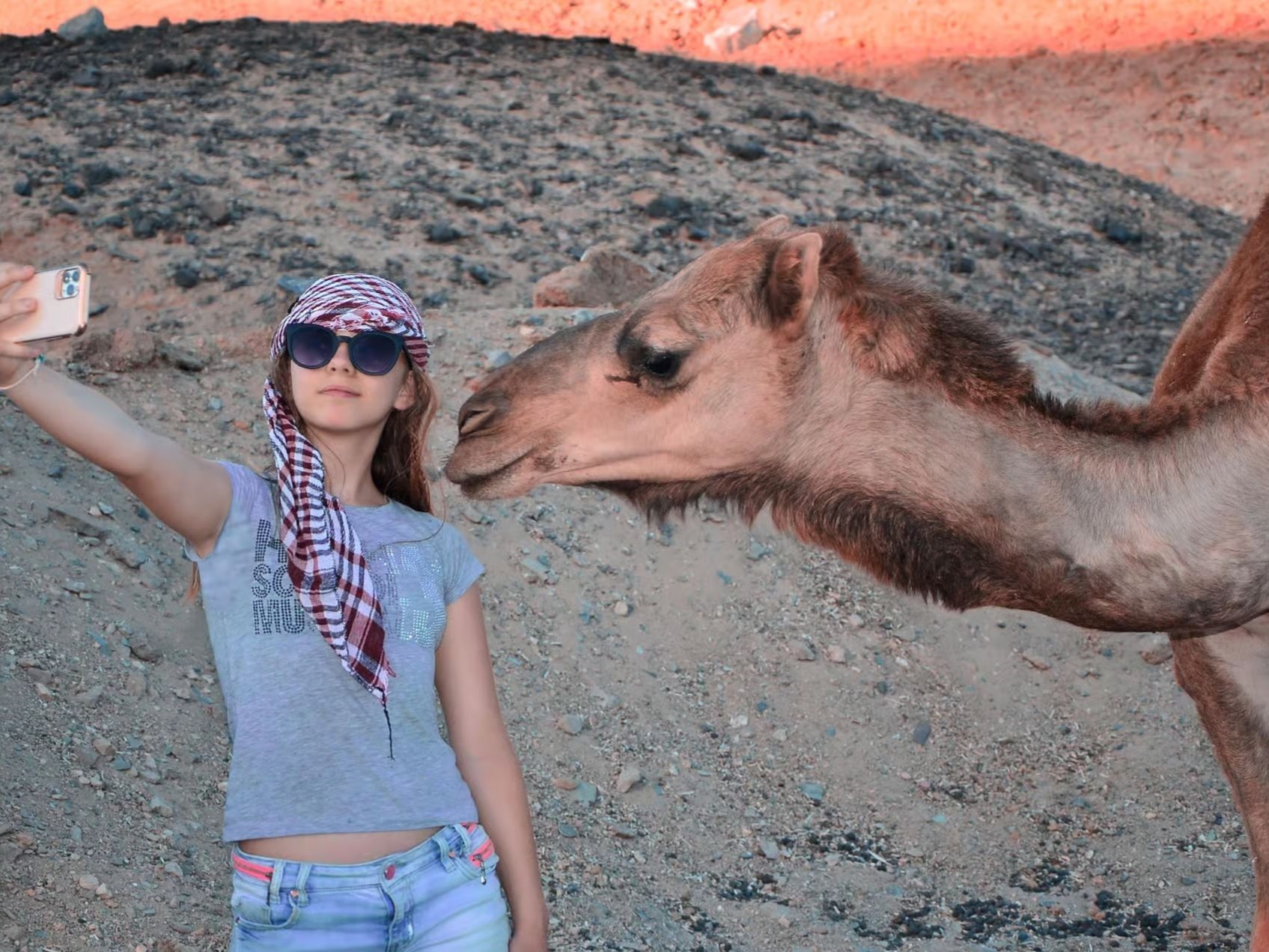 Guest posing beside a camel in the desert